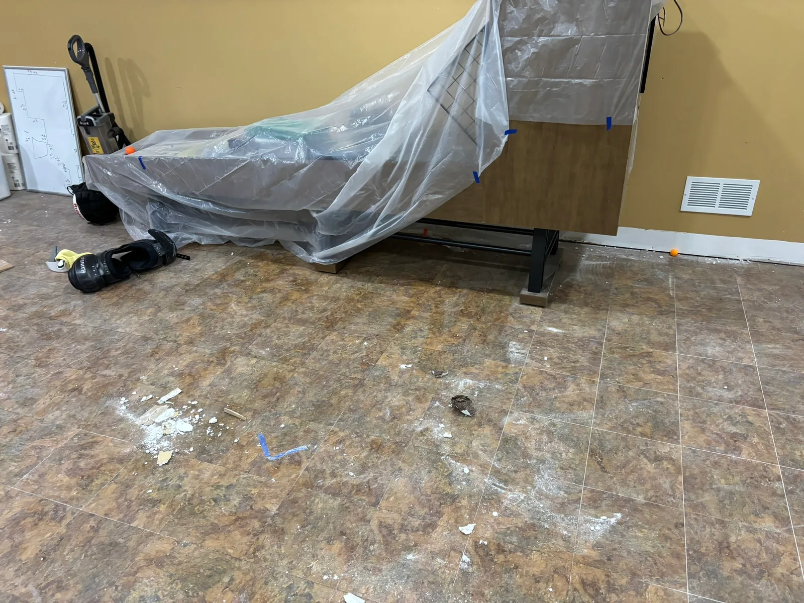 Floor space after the bulky carpet rolls and drywall pile were removed, with covered furniture left in place