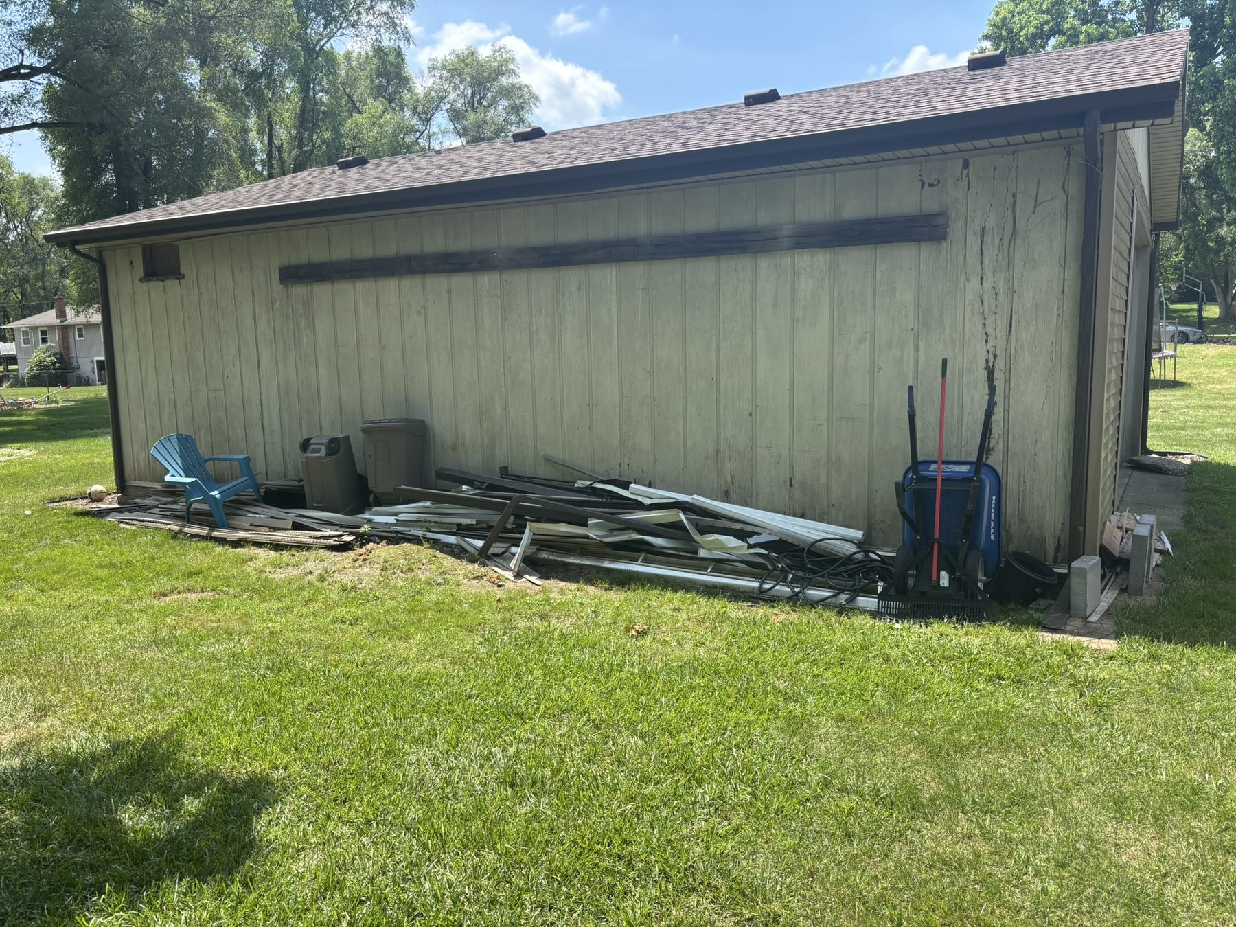Before junk removal with debris stacked along a garage wall